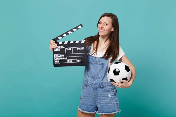 Beautiful young woman football fan support favorite team with soccer ball, classic black film making clapperboard isolated on blue turquoise background. People emotions, sport family leisure concept