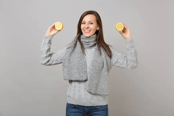 Mujer joven sonriente en suéter gris, bufanda sosteniendo limones aislados —  Fotos de Stock