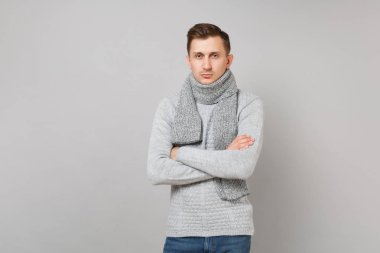 Gri süveterli ciddi genç adam, elele katlanmış eşarp Studio gri duvar arka plan üzerinde izole. Sağlıklı moda yaşam tarzı, insanlar samimi duygular, soğuk sezon kavramı. Kopyalama alanı alay