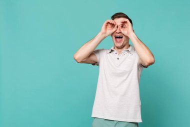 Rahat kıyafetler elele gözler gözlük veya izole mavi turkuaz duvar arka plan üzerinde dürbün taklit yakın gülen genç adam. İnsanlar samimi duygular, yaşam kavramı. Kopyalama alanı alay