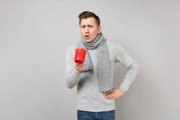 Joven Sorprendido Suéter Gris Bufanda Mirando Taza Roja Café Aislado — Foto de Stock