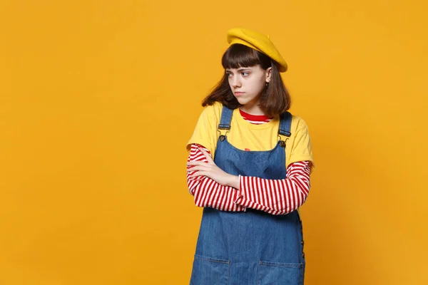 严重女孩少女的肖像在法国贝雷帽 牛仔太阳裙手合置看一边孤立在黄色的墙壁背景 人们真诚的情感 生活方式的理念 模拟复制空间 — 图库照片
