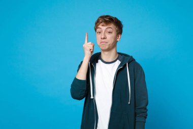 Rahat kıyafetler yeni harika fikir mavi duvar arka planda Studio izole işaret parmağı dayanabiliyor dalgın genç adam portresi. İnsanlar samimi duygular, yaşam kavramı. Kopyalama alanı alay