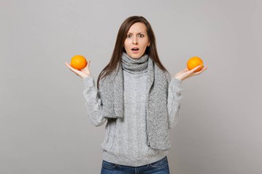 Gri süveterli portakal ISO tutan eşarp çapraşık genç kadın
