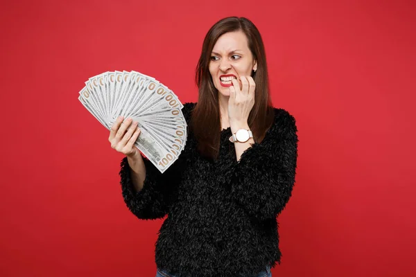 Nervoso giovane donna in maglione di pelliccia nera rosicchiare le unghie, tenendo — Foto Stock