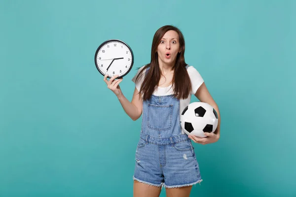 Shocked young woman football fan holding soccer ball, round cloc