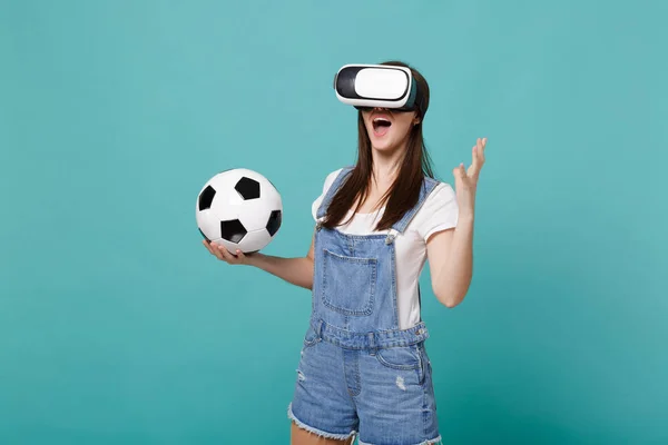 Excited young woman football fan looking in headset holding socc