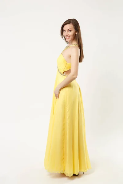 Πλήρες μήκος φωτογραφία μόδας μοντέλο γυναίκα φορούσε κομψό βραδινό φόρεμα κίτρινο φόρεμα θέτοντας απομονωθεί σε λευκό τοίχο φόντο στούντιο πορτρέτο. Κορίτσι μελαχρινή μακριά μαλλιά. Κοροϊδεύετε αντίγραφο χώρου. Πλάγια όψη προφίλ — Φωτογραφία Αρχείου