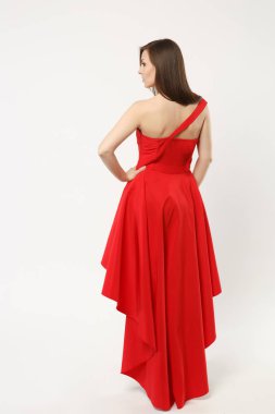 Şık Abiye beyaz duvar arka plan stüdyo portre üzerinde izole kırmızı elbise poz giyen kadın moda modeli tam uzunlukta fotoğraf. Esmer uzun saçlı kız. Kopyalama alanı alay. Arka arka görünüm.