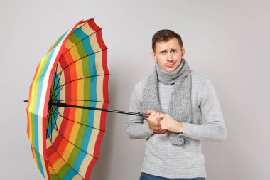 Şaşkın genç adam gri süveterli eşarp renkli umbrel holding