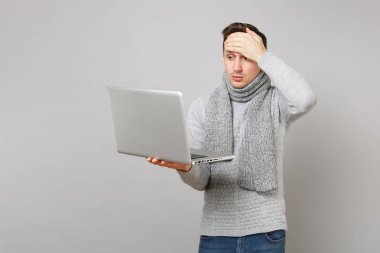 Genç adam gri süveterli eşarp dizüstü pc bilgisayar üzerinde çalışıyor, 