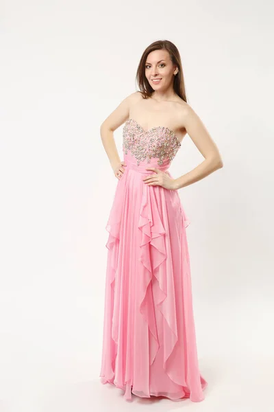 Full length photo of fashion model woman wearing elegant evening dress gown posing isolated on white wall background studio portrait. Brunette long hair girl. Mock up copy space. Pink dress face view. — Stock Photo, Image