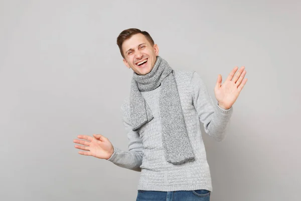 Riéndose joven en suéter gris, bufanda extendiendo las manos aislado — Foto de Stock