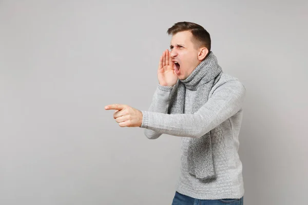 Αυστηρή άνθρωπος σε γκρι πουλόβερ, κασκόλ ψάχνει στην άκρη, ουρλιάζοντας με — Φωτογραφία Αρχείου