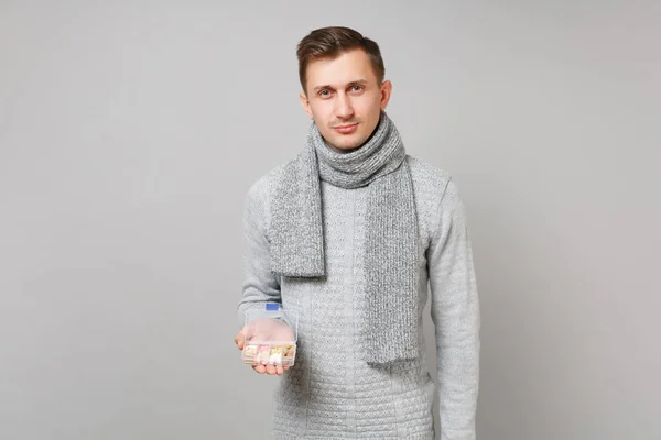 Hombre joven atractivo en suéter gris, bufanda celebración píldora diaria b — Foto de Stock