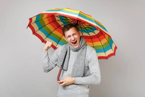 Χαρούμενος νεαρός άνδρας σε γκρι πουλόβερ, κασκόλ κρατώντας ομπρέλα — Φωτογραφία Αρχείου