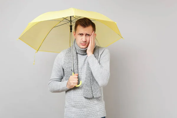 Trött ung man i grå tröja, halsduk innehar gult paraply p — Stockfoto