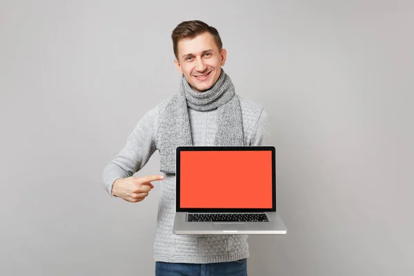Νεαρός άνδρας σε γκρι πουλόβερ, κασκόλ κατάδειξης δείκτη σε φορητό υπολογιστή — Φωτογραφία Αρχείου