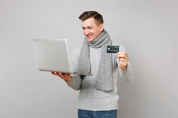 Mladý muž v šedém svetru, šátek držet kreditku banky, pracovat na — Stock fotografie