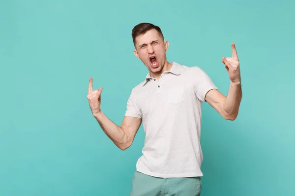 Divoký mladý muž v neformálním oblečení křičí, ukazující rohy nahoru ges — Stock fotografie