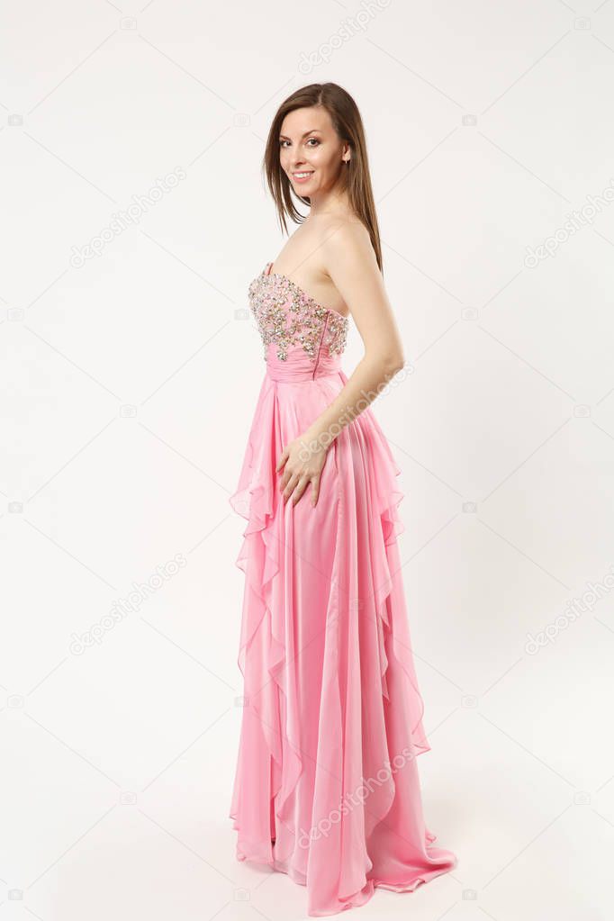 Full length photo fashion model woman wearing elegant evening dress pink gown posing isolated on white wall background studio portrait. Brunette long hair girl. Mock up copy space. Side profile view.