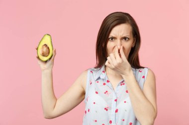 El ile burun kapsayan memnun genç kadın, pembe pastel duvar arka planda izole taze olgun yeşil avokado meyve yarısını tutun. İnsanlar canlı yaşam tarzı tatil konsepti rahatlayın. Kopya alanı mock.