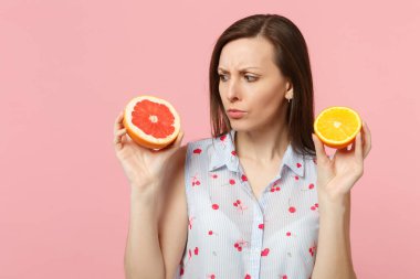 Yaz elbiseleri taze olgun greyfurt, pembe pastel duvar arka planda izole turuncu meyve halfs tutan ilgili genç kadın. İnsanlar canlı yaşam tarzı tatil konsepti rahatlayın. Kopya alanı mock.