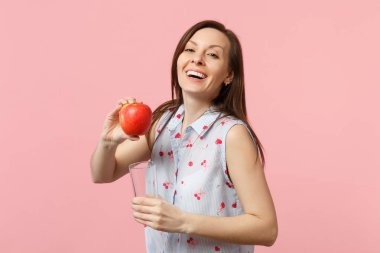 Yaz kıyafetlerine gülen genç kız taze Olgun kırmızı elma meyve cam bardak pembe pastel duvar arka planda izole stüdyo. İnsanlar canlı yaşam tarzı tatil konsepti rahatlayın. Kopya alanı mock.