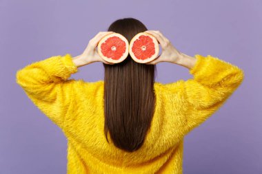 Mor pastel arka planda izole saç yakın taze olgun greyfurt halfs tutan kürk kazak genç kadının arka arka görünümü. İnsanlar canlı yaşam tarzı, tatil konsepti rahatlayın. Kopya alanı mock.