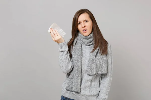 Αναστατωμένος νεαρή γυναίκα με γκρι πουλόβερ, κασκόλ κρατώντας χαρτί πετσέτα FO — Φωτογραφία Αρχείου