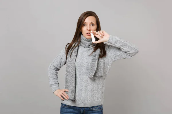 Mujer joven perpleja en suéter gris, sujeción bufanda usando dr nasal — Foto de Stock
