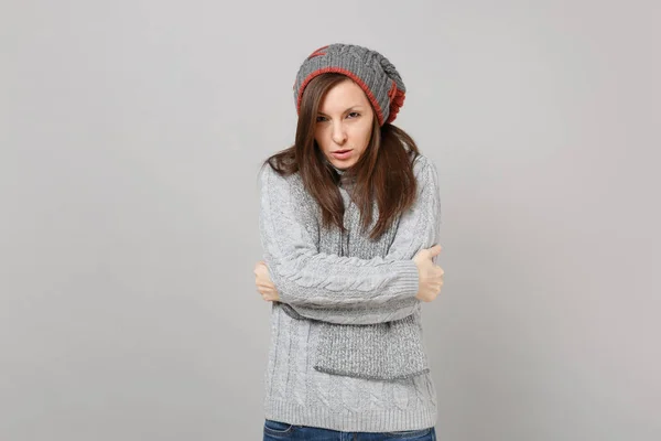 Замерзающая молодая женщина в сером свитере, шарф в шляпе, держась за руки — стоковое фото