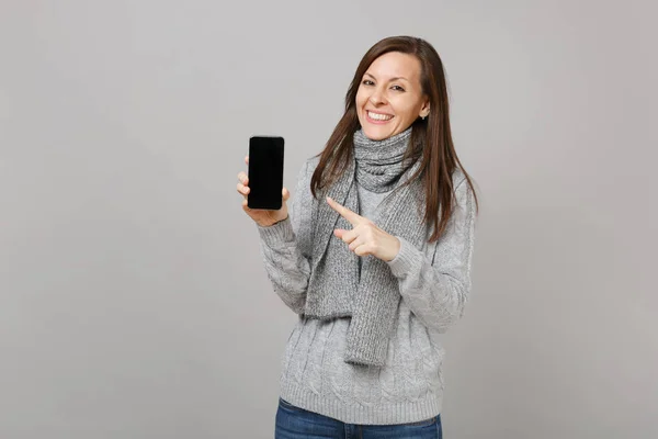 Uśmiechnięta kobieta w szarym swetrze, szalik wskazujący palcem wskazującym na mo — Zdjęcie stockowe
