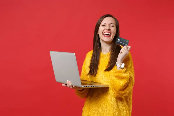 Smějící se mladá žena ve žlutém kožešním svetru držící kreditní banku c — Stock fotografie