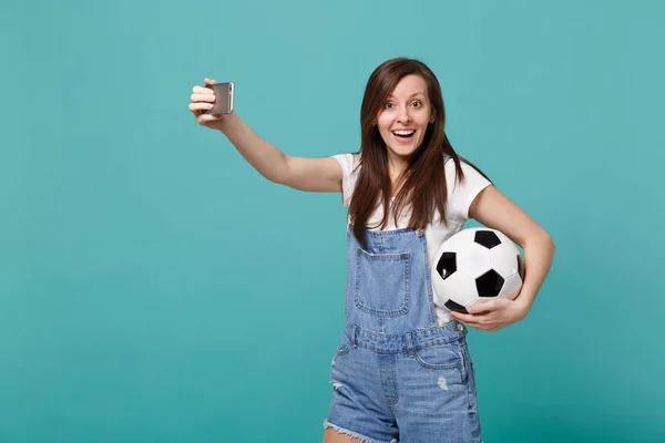 Excited young woman football fan with soccer ball doing selfie s