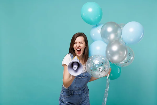 Angry young woman in denim clothes screaming in megaphone while