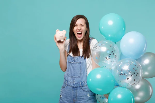 Crazy screaming funny young girl in denim clothes holding piggy