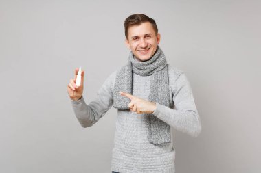 Gri kazak gülümseyen genç adam, atkı işaret indeksi tutan 