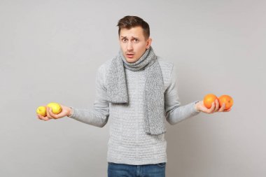 Gri kazak, eşarp tutan portakallar, LEMO içinde perplexed genç adam