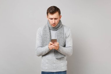 Gri kazak, cep telefonu Pikal kullanarak eşarp şaşkın genç adam