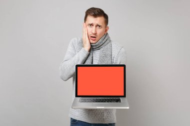 Gri kazak genç adam, eşarp yanak el koydu, LAPT tutarak