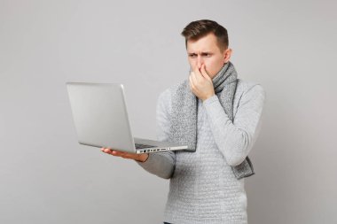 Genç adam gri süveterli eşarp dizüstü pc bilgisayar üzerinde çalışıyor, 