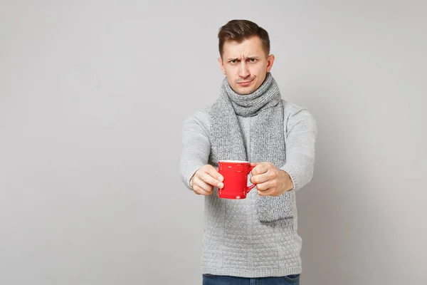 Gri kazak şaşkın genç adam, COFF kırmızı fincan tutan eşarp — Stok fotoğraf