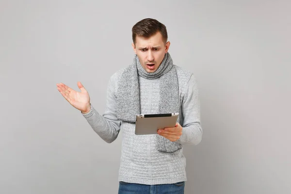 震惊的年轻人在灰色毛衣, 围巾使用平板电脑计算 — 图库照片