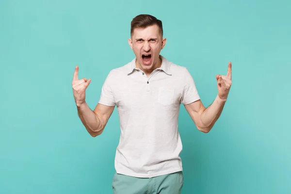 Křičící mladík v příležitostných šatech zobrazující rohy gesto — Stock fotografie