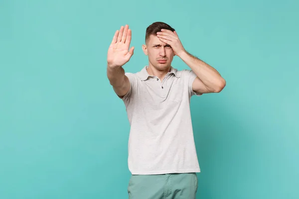 Esausto giovane uomo in abiti casual mettendo mano sulla fronte a — Foto Stock