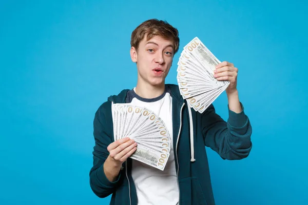 Portret zdumiony młody człowiek w casual ubrania trzymać fan pieniędzy — Zdjęcie stockowe