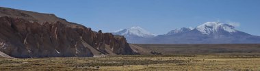 Snow capped peak of Volcano Guallatiri towering over the Lauca River valley high on the Altiplano of northern Chile in Lauca National Park. clipart