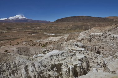 Aşınmış kaya oluşumları Quebrada Chuba, yüksek Dağları kuzey Şili Lauca Millî Parkı'nda bir Nehri Vadisi boyunca. Kar pik volkan Guallatiri mesafe şapkalı.
