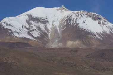 Snow covered Guallatiri volcano (6063 m) towering above the Altiplano in Lauca National Park, northern Chile. clipart